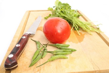 Cutting board with coriander, tomato and green chili
