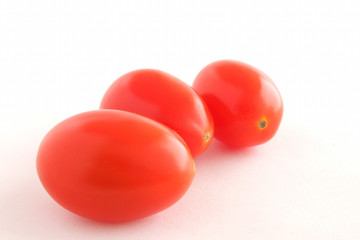 Three baby tomatoes on black background