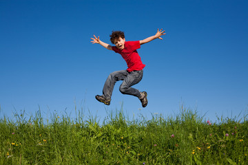 Boy jumping, running against blue sky