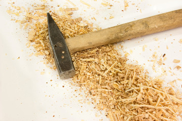 Hammer lying among the sawdust on a white background
