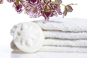 Spa items with white towels, natural soap and orchid