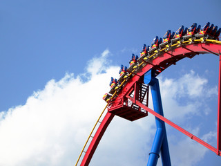 People in roller coaster againt bright blue sky