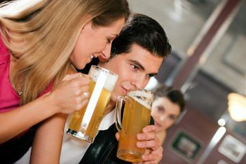 Paar in einer Bar trinkt Bier und flirtet