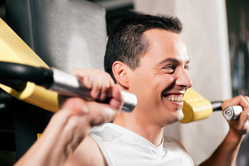 Mann trainiert am Gerät im Fitnessstudio