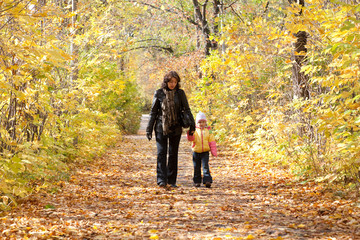 Obraz premium Mother and daughter walk on foot on autumnal park