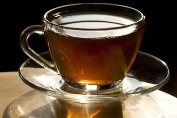 hot tea amber color is poured into a glass cup