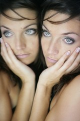 Beautiful woman on the mirror as a twins portrait