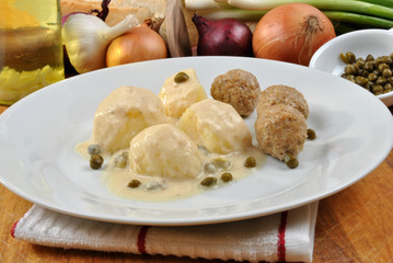 cooked meatballs in a white sauce with capers