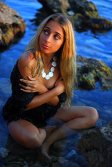 Young beautiful fresh woman sitting on a stone