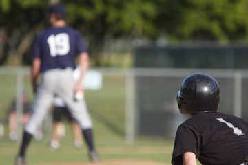 Runner on first base watching the pitcher.