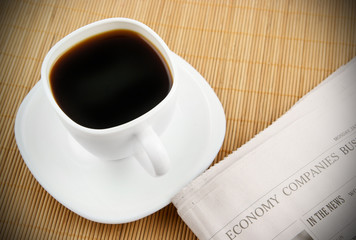 Coffee cup and newspaper on wooden background