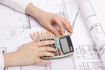 hands with house construction plan, calculator and money