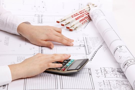 hands with house construction plan and calculator