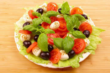 Fresh salad with basil, mozzarella, olives and tomato