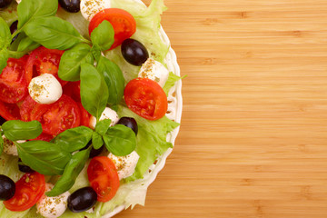 Fresh salad with basil, mozzarella, olives and tomato