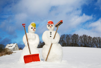 snowwoman and snowman with snow shovel and broom