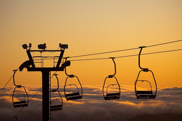 ski lift over clouds in sunset
