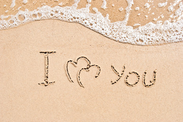 inscription on sand I love you and two connected hearts