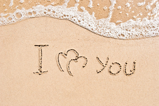 inscription on sand I love you and two connected hearts