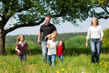 Fototapeta premium Familie rennt über eine Wiese im Frühling