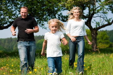 Family running on meadow in spring