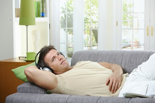 Man on sofa listening to music smiling