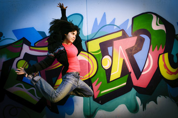 Mädchen springt vor bemalter Wand