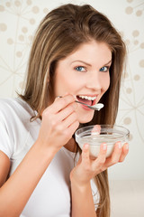 Young attractive woman eating yogurt