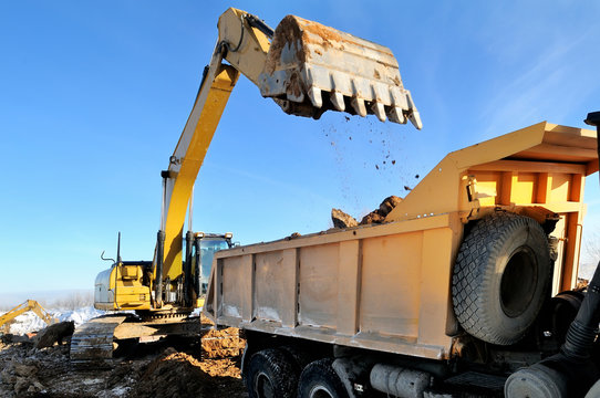 loader excavator loading earth to body of rear-end tipper