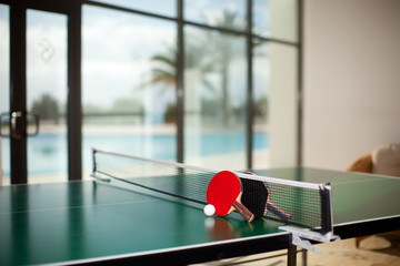 Table tennis rackets and ball, pool in the background