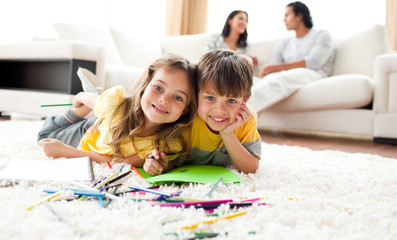 Adorable btother and sister drawing lying on the floor