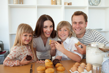 Obraz na płótnie Canvas Cute children eating muffins with their parents