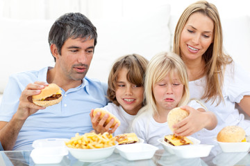 Obraz na płótnie Canvas Merry family eating hamburgers