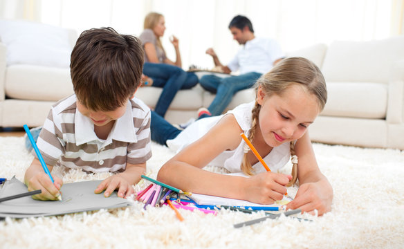 Concentrated siblings drawing lying on the floor