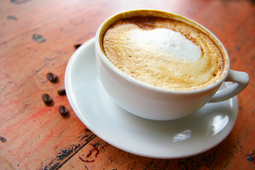 cup of frothy cappuccino coffee with coffee beans