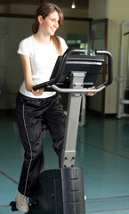 Happy young woman in the gym biking