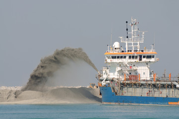 Dredge ship pipe pushing sand to create new land