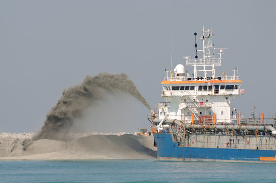 Dredge ship pipe pushing sand to create new land