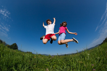 Kids jumping, running against blue sky