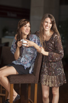 Two young women drinking coffee at a bar