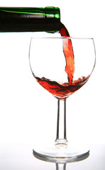 Red wine being poured into glass and a green bottleneck