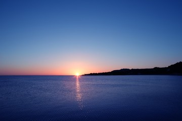 Fototapeta na wymiar Beautiful sunset sunrise over blue sea ocean red sky