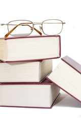 pile of books with glasses over it