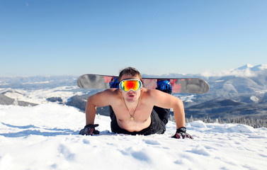 Snowboarder topless on the mountain slope