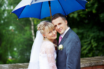 Happy bride and groom at wedding under an umbrella