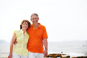 Happy mature couple walking along the beach.