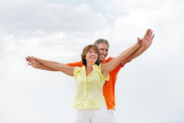 Fototapeta na wymiar Happy mature couple standing with arms outstretched.