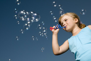 Little girl playing with soap bubbles