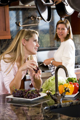 Teenage girl in kitchen chatting with mother