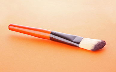 cosmetic brush on the orange background